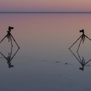 Cameras and tripod reflected on water at Lake Eyre